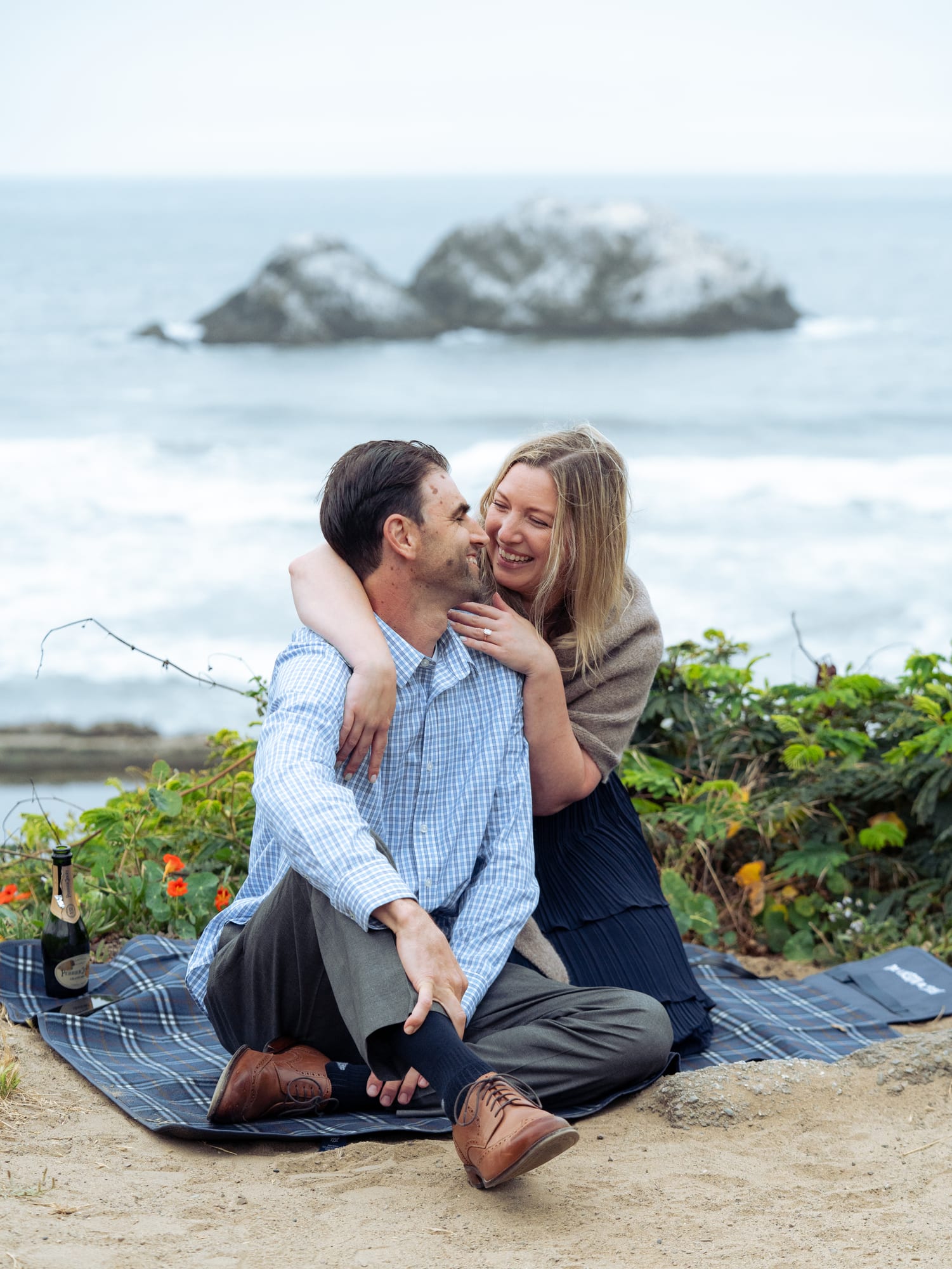 Close portrait of the couple foreheads touching, both laughing, her hair loose in the wind