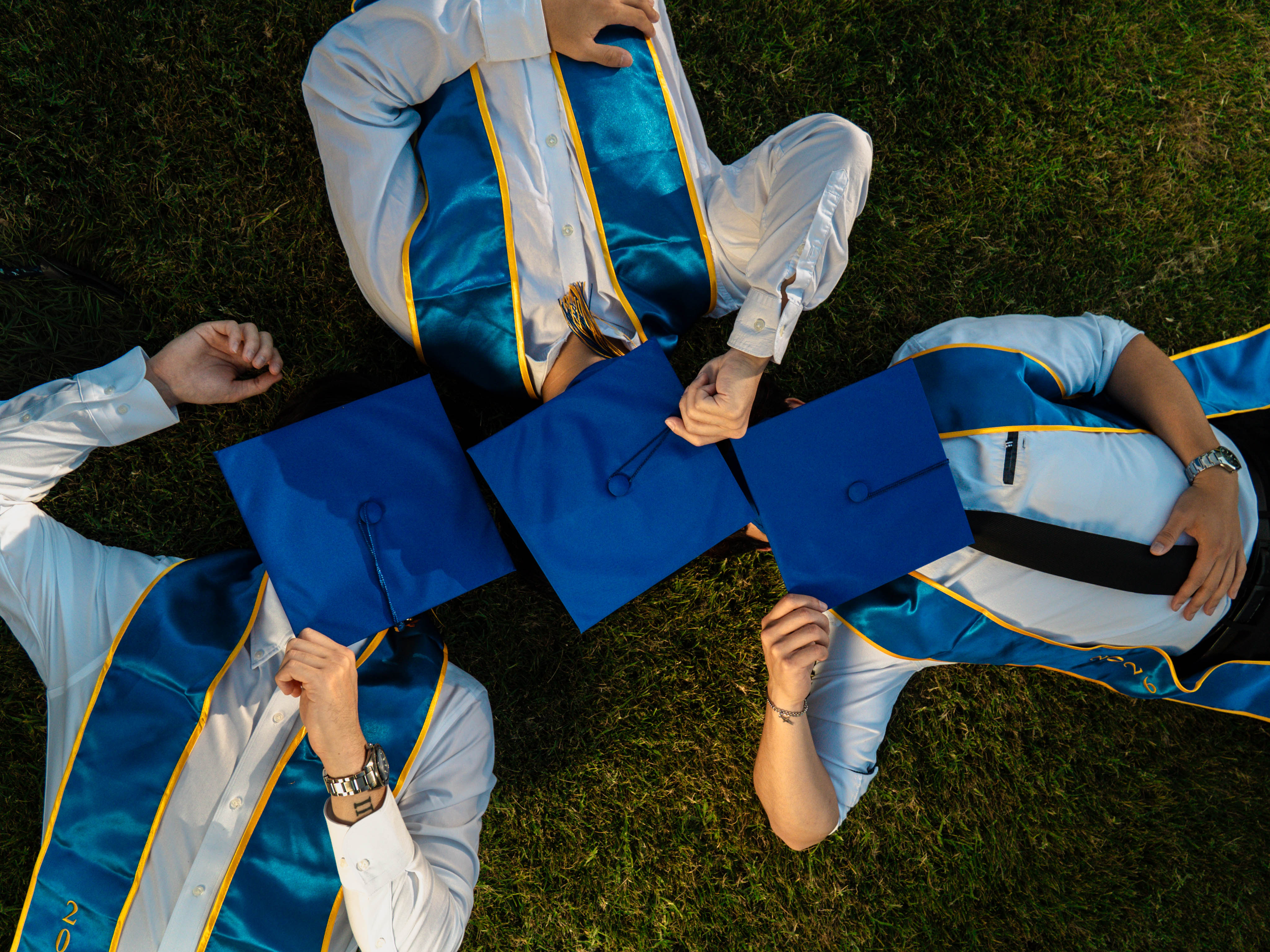 Overhead view of SJSU graduates holding their caps together in a row