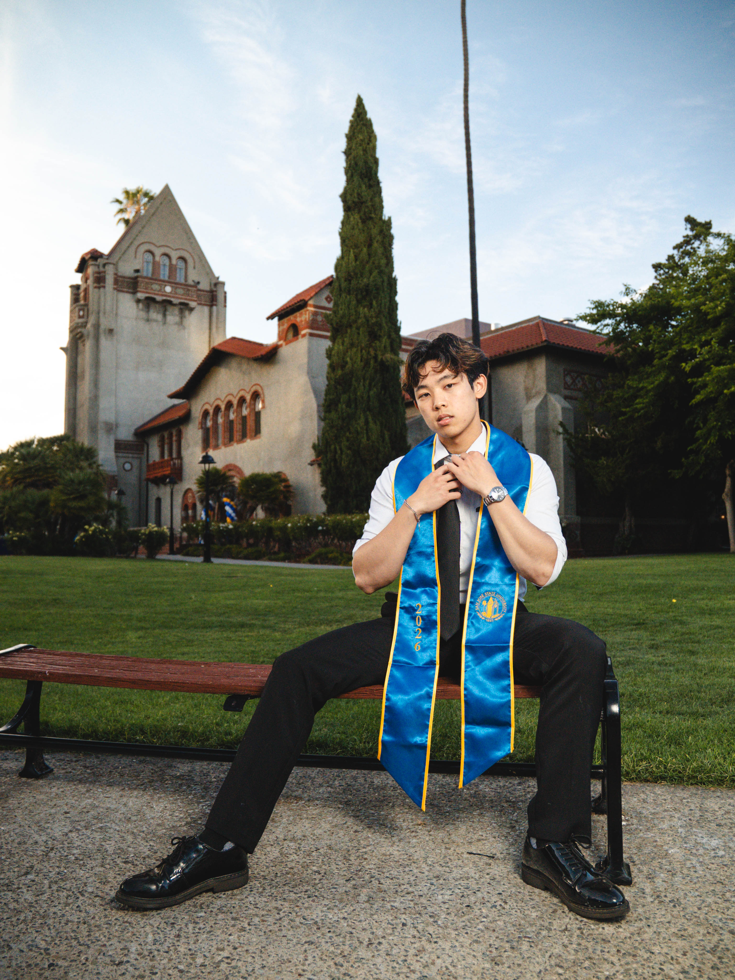 San Jose State graduate portrait in cap and gown among palm trees