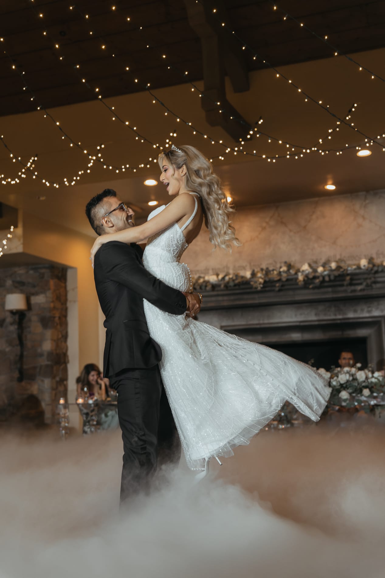 Groom lifting the bride off the floor during their first dance in low fog