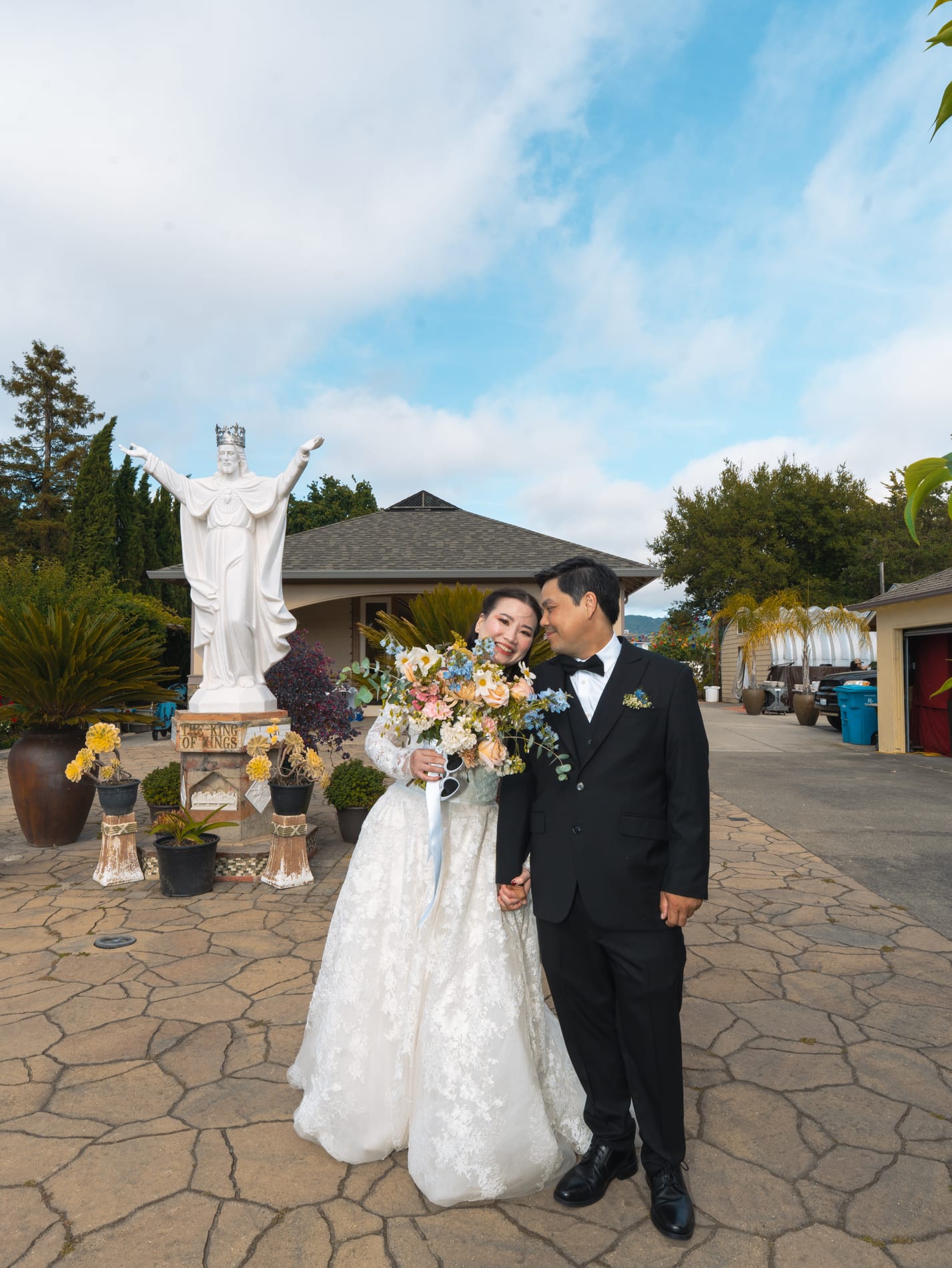 Groom kissing the bride's cheek outside the church, her peach and white bouquet in hand